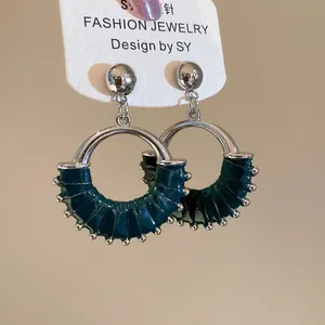 Detail of silver hoop earrings featuring teal ribbon wrap and tiny metallic beads
