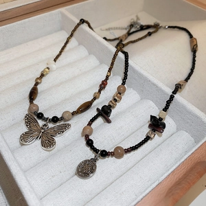 Detailed shot of handmade beaded necklaces with butterfly and round pendants in velvet box