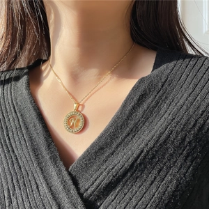 Close-up of golden letter N pendant necklace with sparkling zircons on a model
