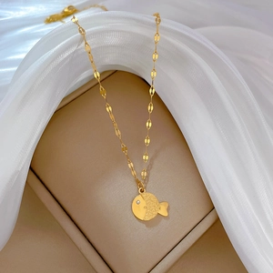 Macro detail of gold fish pendant with crystal eye and flat link chain in a gift box