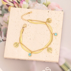 Detalle de pulsera dorada de doble capa con árbol de la vida y piedra turquesa