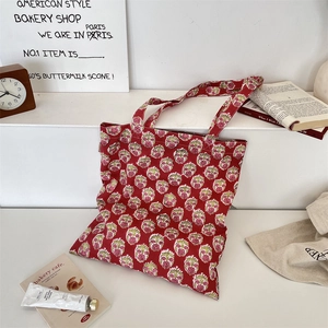 Detail of red floral canvas tote bag with retro flower pattern and long shoulder straps