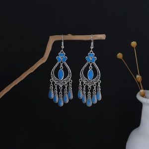 Detail view of Bohemian silver earrings with blue enamel dangles on wooden branch