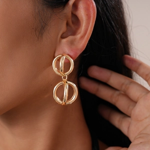 Macro detail of glossy geometric hollow interlocking gold hoop earrings on a model