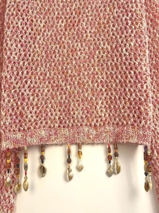 Detail of bohemian knit top featuring lace-up tassels with wooden beads and shells