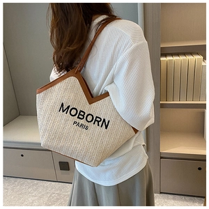 Detail of straw woven bucket bag with leather straps and embroidered PARIS logo