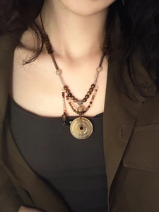 Close-up of retro necklace featuring a brown stone ring pendant with woven cord beads