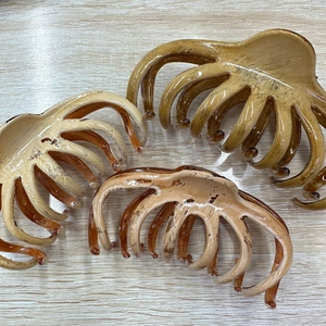 Detail showing three large oil painting style hair claws in brown and beige colors