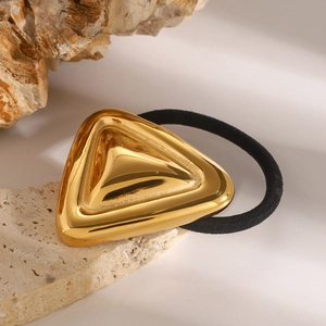 Geometric gold triangle hair tie with black elastic band on natural stone background
