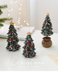 Detail view of miniature resin Christmas tree with red bows and golden star topper