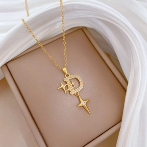 Macro shot of gold D-letter star pendant with shimmering crystals on white silk