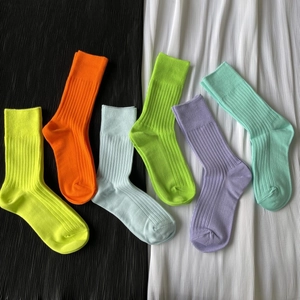 Flat lay of six colorful ribbed cotton mid-calf socks in vibrant neon and pastel shades