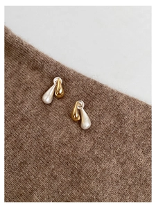 Detailed view of two-tone teardrop earrings with gold and silver finish on knit fabric