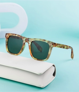Detail of tortoise shell sunglasses with green lenses on white foldable case
