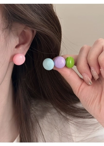 Détail macro d'un lot de boucles d'oreilles macaron rose bleu violet et vert