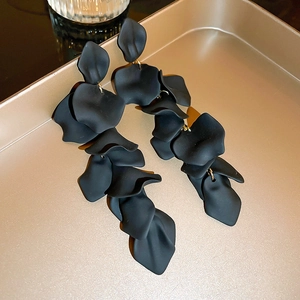 Macro shot of long black petal tassel earrings with matte finish on golden metal tray