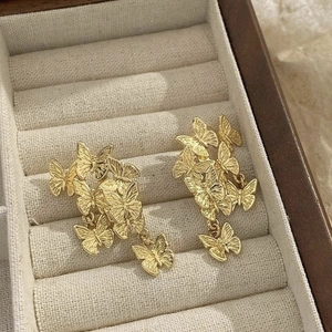 Detail showing gold butterfly earrings on a soft cream jewelry velvet display tray