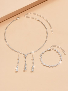 Detailed four-piece silver bridal jewelry set with sparkling rhinestones on pink background