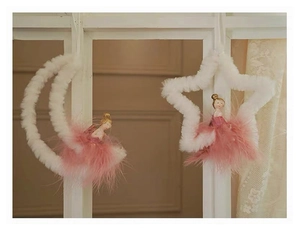 Detail of plush angel ornaments with pink feathers hanging on a white window frame