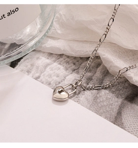 Detailed macro view of silver-toned heart lock pendant on a stylish Figaro chain necklace