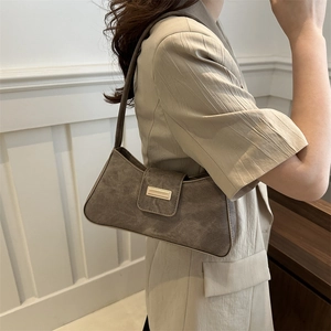 Brown suede baguette shoulder bag with metallic buckle shown on a female model