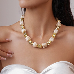 Detail of beaded necklace with gold metal accents and off-white marble texture beads
