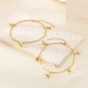 Détail de deux bracelets de cheville dorés avec perles et fermoir mousqueton