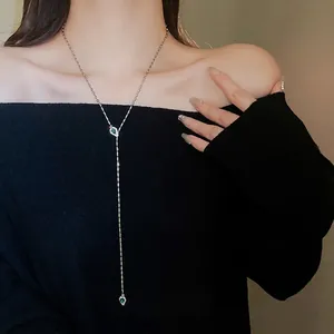 Elegant gold-tone Y-shaped necklace with green emerald teardrops and crystals on a black sweater