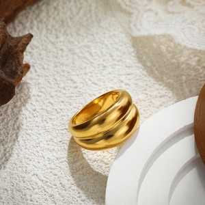 Macro shot of minimalist dual-layer wide 18K gold ring on a textured stone background