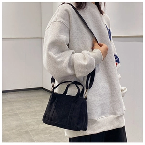 Detail showing the ribbed corduroy texture and detachable strap on black mini Boston bag