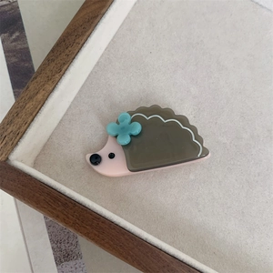 Close-up of pink hedgehog acetate hair clip with a small green clover flower detail
