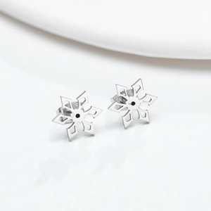Polished stainless steel snowflake stud earrings with black center on white background