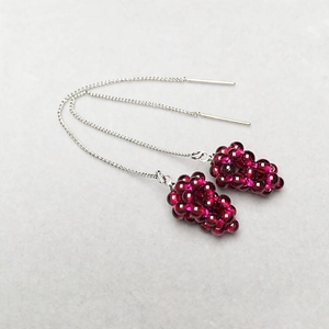 Close-up of handmade garnet grape cluster earrings with red beads and silver chain