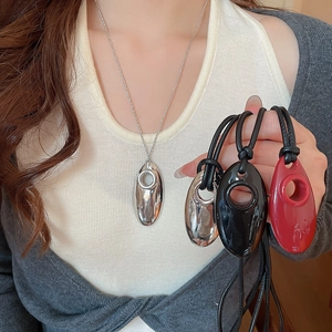 Macro detail of geometric pebble pendant necklaces in silver, black and red finishes