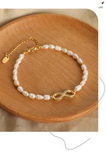 Detail of freshwater pearl bracelet featuring a gold infinity charm with micro-zircon stones