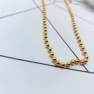 Close-up of golden beaded titanium steel necklace on a minimalist geometric background