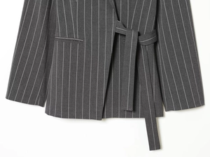 Detail of dark grey striped blazer showing fine fabric texture and tie-waist belt design