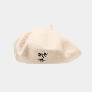 Close-up of beige wool beret featuring detailed black coconut tree embroidery detail