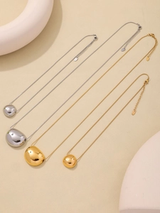 Flat lay of gold and silver pebble pendant necklaces on minimalist geometric props