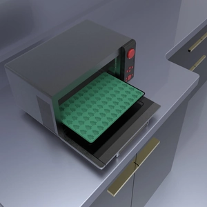 Green silicone Christmas tree mold being placed into a modern oven on a baking tray
