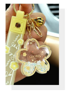 Close-up of a yellow Sakura acrylic quicksand keychain with an embossed lucky strap.