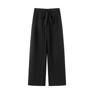 Detail of black quilted wide-leg cotton pants featuring a drawstring waistband on white background