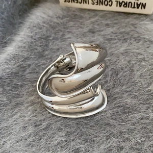 Makroaufnahme vom silbernen Faltenband-Ring mit skulpturaler, gewellter Spiegelfläche