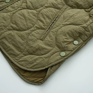 Detail der armee-grünen Steppjacke mit winddichtem Stoff und seitlichen Druckknöpfen