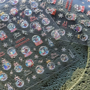 Macro detail of 5D embossed Christmas nail stickers featuring 3D Santa and crystal balls