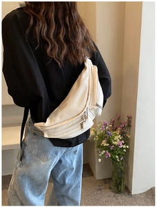 Detail view of the cream white crossbody bag with multiple zipper compartments and wide strap