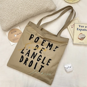 Detail of khaki canvas tote bag with black French poetry print in a cozy lifestyle setting