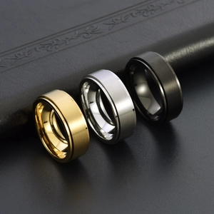 Detail of three rotating rings in gold, silver, and black with brushed steel texture