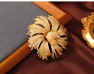 Close-up of vintage matte gold flower brooch showing intricate brushed metal texture