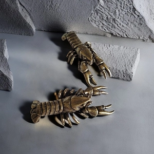 Detailed close-up of brass lobster figurines with vintage texture on grey stones